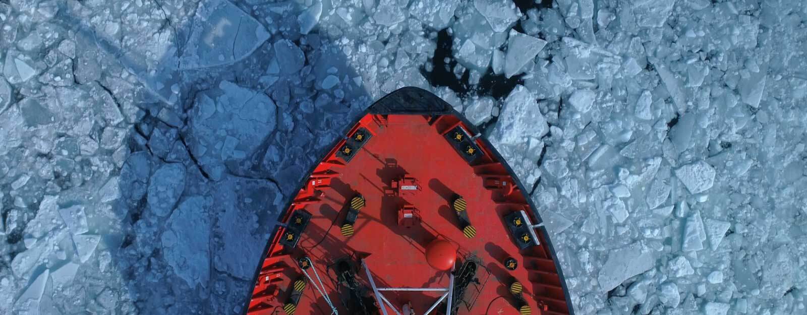 tip of a large red boat coasting through cracked ice